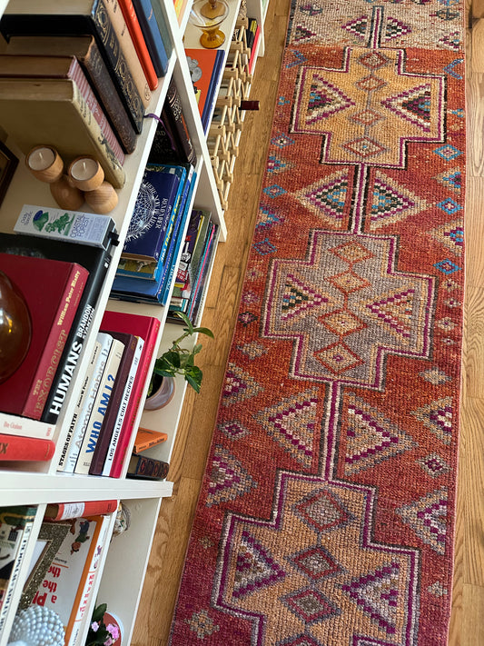 Bookshelf with books and a patterned rug on a wooden floor